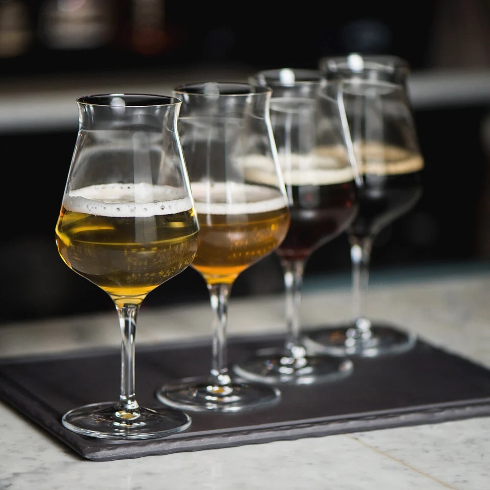 4 Biergläser mit verschiedenen Biersorten gefüllt auf dunkler Platte diagonal aufgestellt, Serie Birrateque, 420 ml