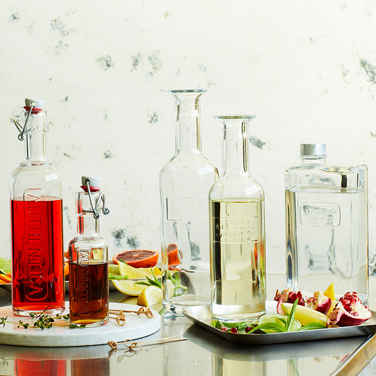 Glasflaschen Optima, unterschiedliche Formen und Größen, mal gefüllt, mal leer mit Dekoration auf einem Tisch